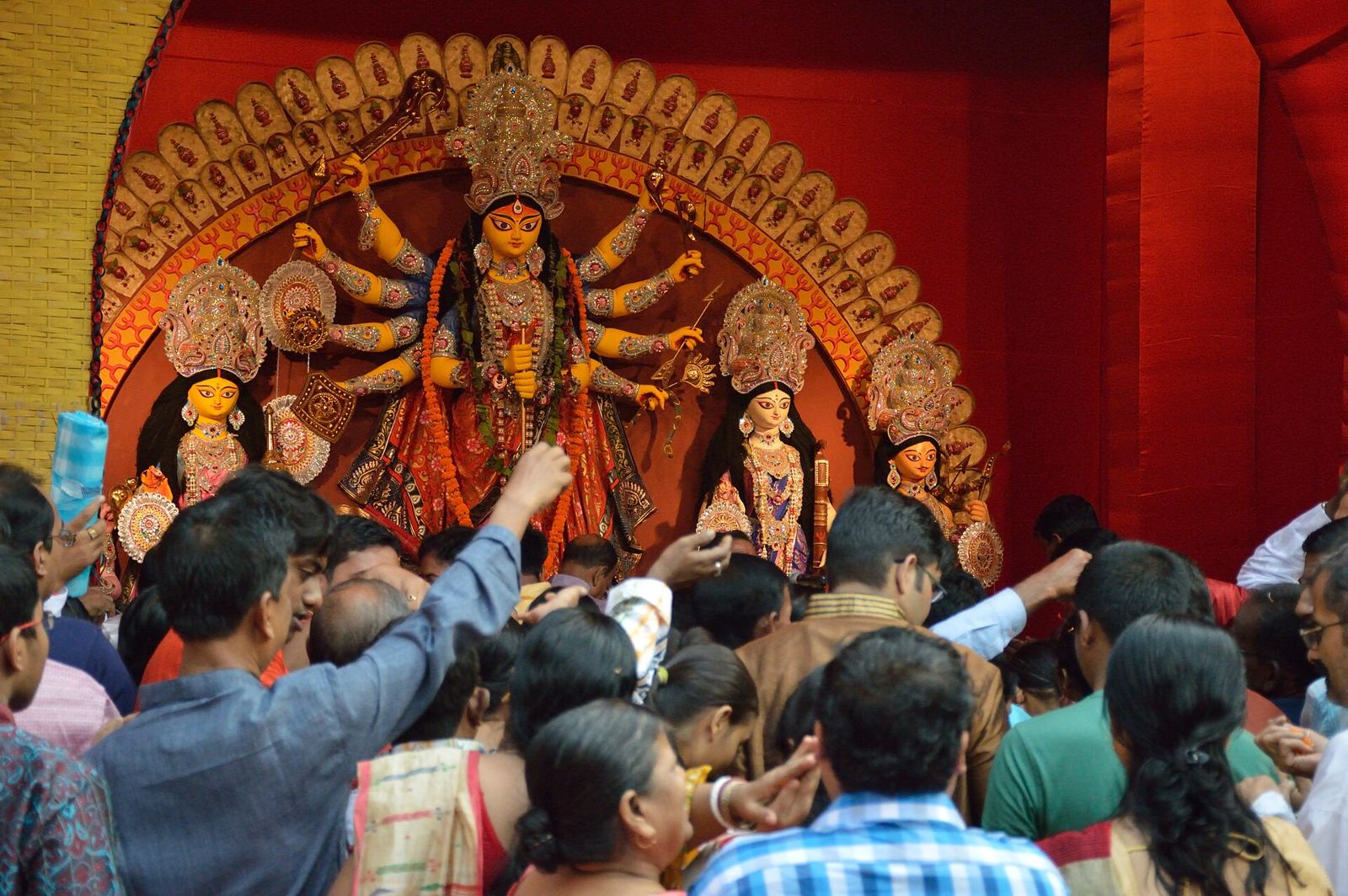 A crowd raises flowers towards the goddess during the morning anjali