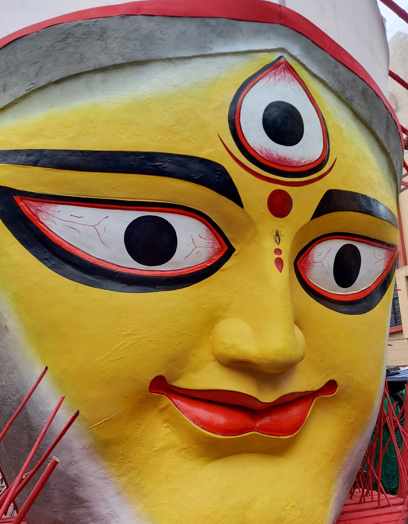 The painted face of the goddess Durga, her third eye open, on a giant pandal sculpture